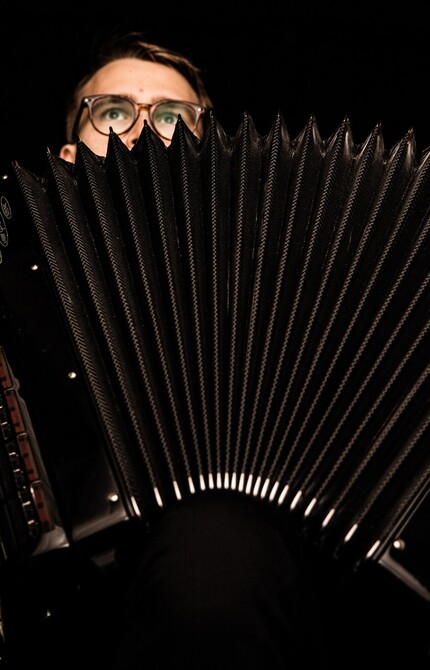 Person holding an open accordion, showcasing the instrument's keys and bellows.