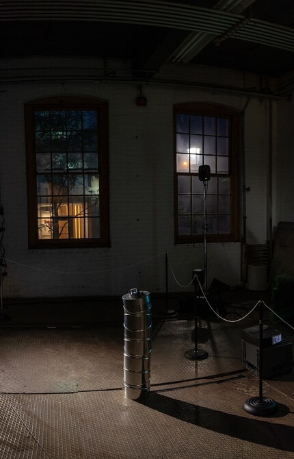 An old-looking, dark room with two windows housing equipment. A spotlight is pointed at the center of the room.