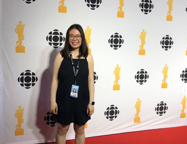 Emily Tam stands in on the red carpet at the Juno awards. The banner in the background has a repeating pattern of the CBC and Juno Awards logo.