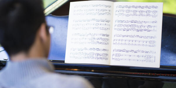 Student looking playing piano with score