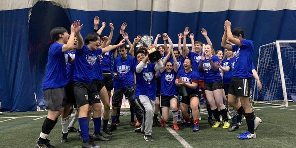 Intramural sports team in blue jerseys holding a trophy and celebrating.