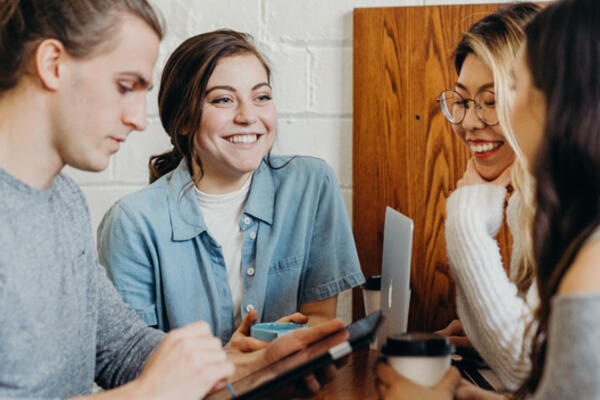 Thumbnail Image for Student talking and smiling over coffee and computers