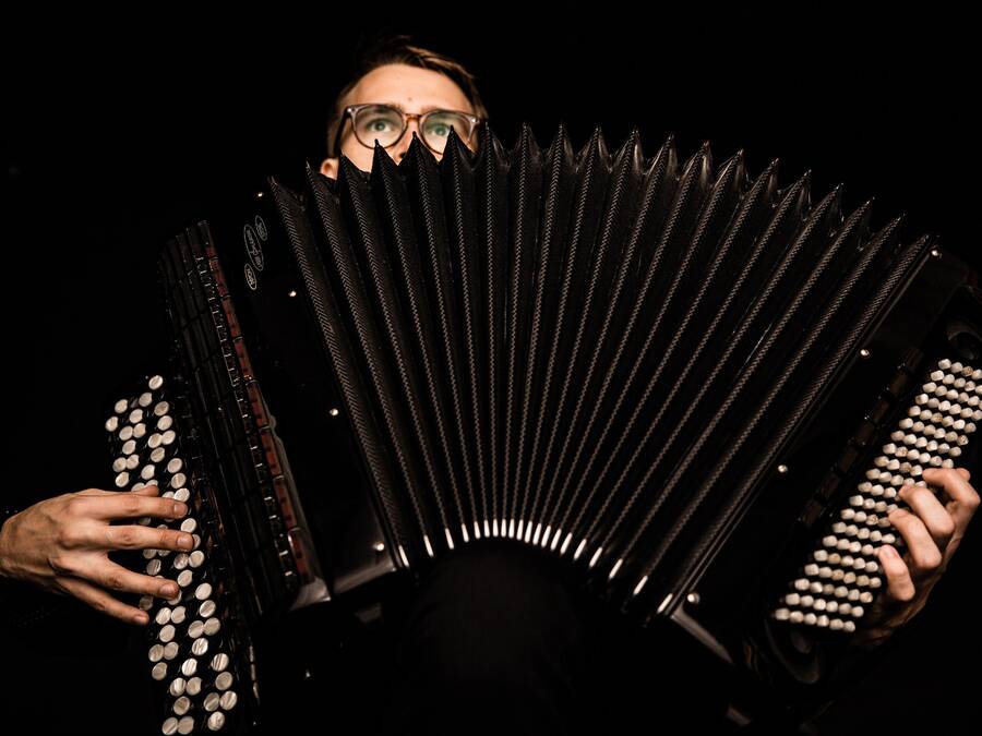 Person holding an open accordion, showcasing the instrument's keys and bellows.