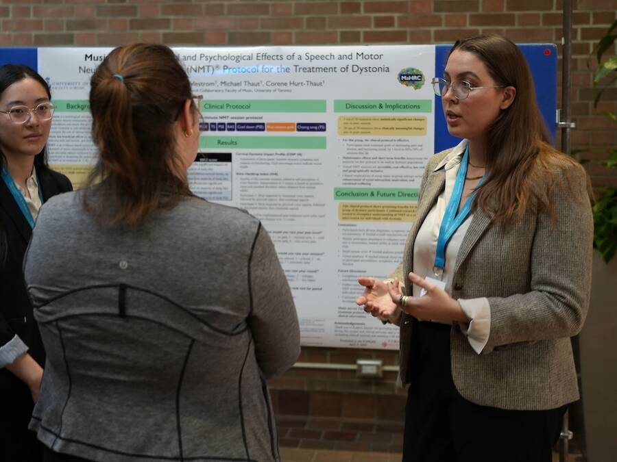 Two people giving a presentation to one person, with an information board in the background.