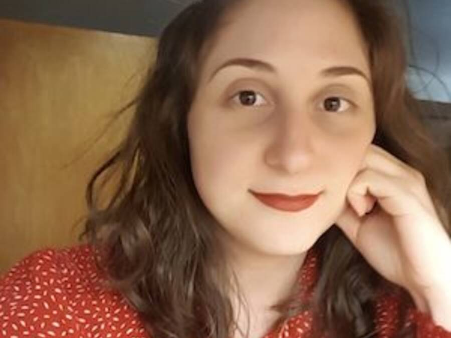 Headshot of a person wearing a red polka dot blouse, resting their hand gently on their face, with a warm and thoughtful expression.