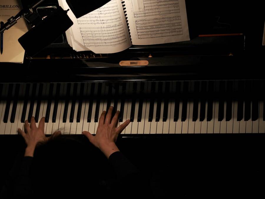 Overhead view of a person playing the piano in an orchestra pit, with their hands on the keys.