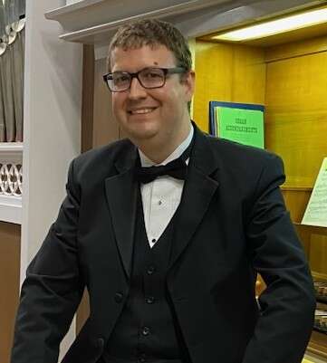 Headshot of Aaron James standing in front of a display case.