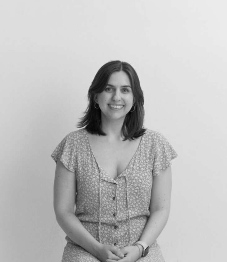 Black and white portrait of Kristen Antunes sitting down and smiling