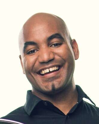 Headshot of a person wearing a black shirt, smiling warmly against a white background.