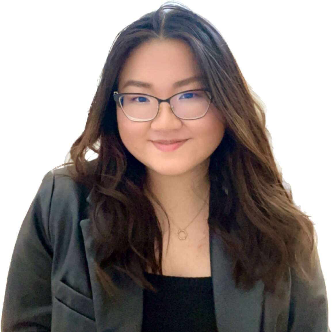 person with long hair wearing glasses and a blazer, smiling.