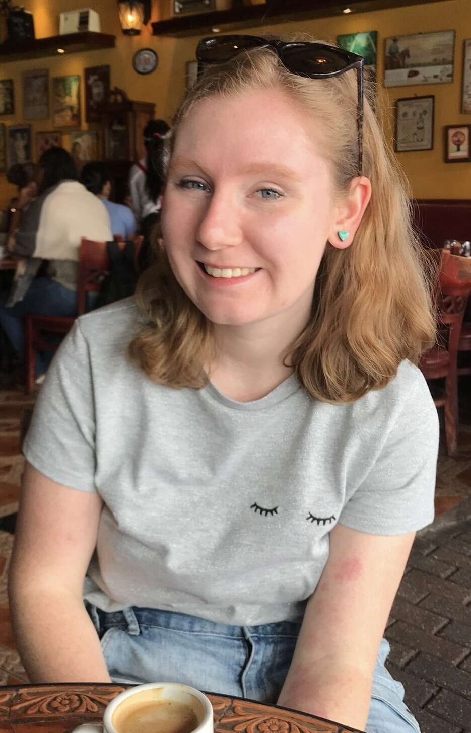 Person with shoulder length hair smiling in a coffee shop