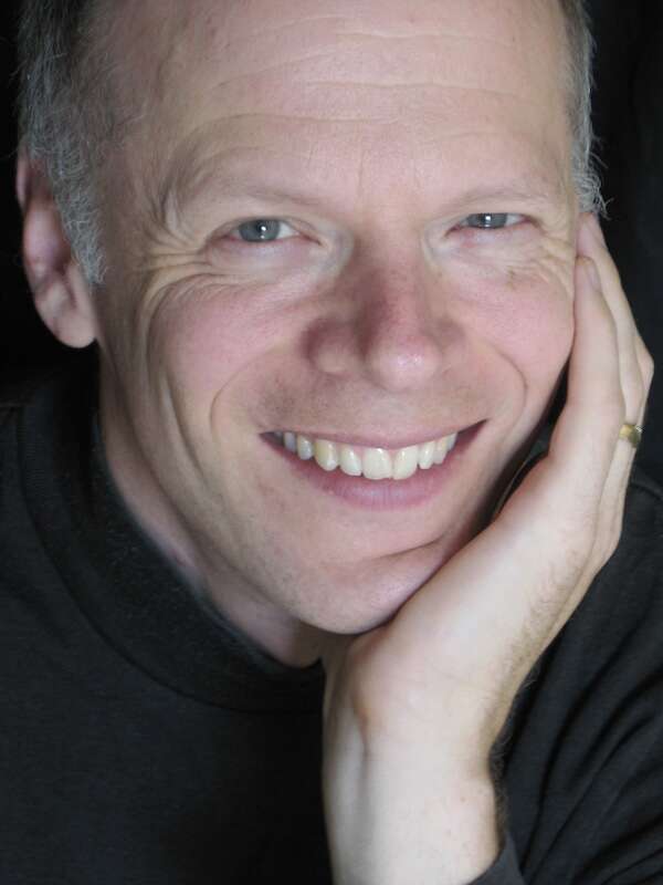 Person wearing a black shirt, smiling and gently holding their face, creating a warm and approachable expression.