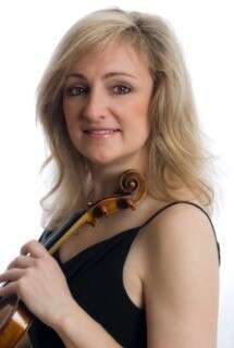 A headshot of a person with shoulder-length blonde hair, wearing a black tank top and holding a violin, set against a white background.