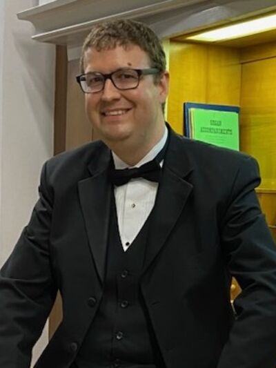 Headshot of Aaron James standing in front of a display case.