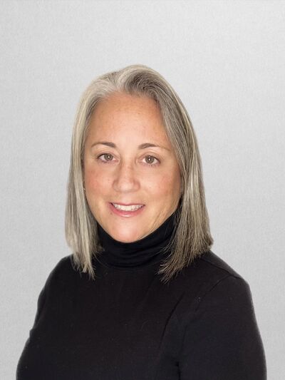 Woman wearing a black shirt, smiling at the camera, with a white background.