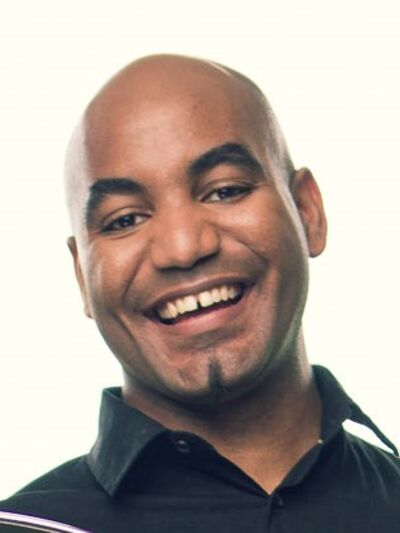 Headshot of a person wearing a black shirt, smiling warmly against a white background.