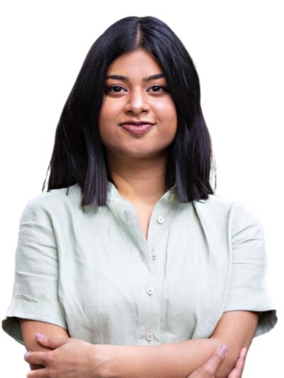 Headshot of a person with shoulder-length hair, wearing a grey shirt, standing in front of a white background, with a neutral or friendly expression.