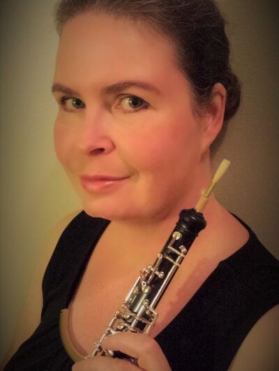 erson with a low bun wearing a black tank top, holding an oboe.