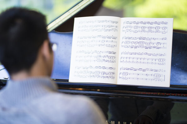 Student looking playing piano with score