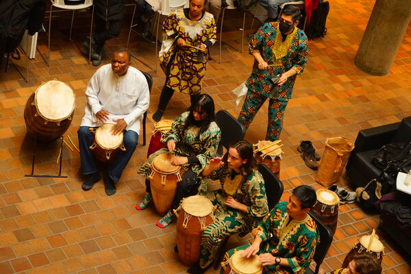 Members of the Afican Drumming Ensemble perform with hand drums and colourful outfits.