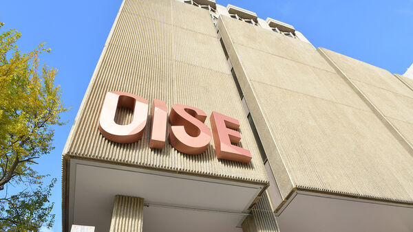 Upward-looking front view of the OISE building, showcasing its tall, modern architecture.