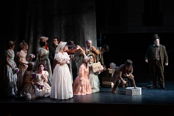 Scene from an opera, featuring a group of people in Regency-era costumes performing on stage.