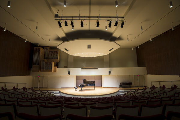 Empty performance hall with a grand piano placed on the stage, highlighting the spaciousness of the venue.